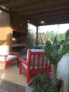 a patio with two red chairs and a table at Mar y Cerros in Piriápolis