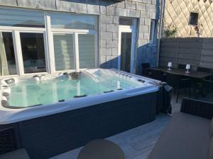 un bain à remous dans un patio avec une table dans l'établissement Maison avec Jacuzzi 5ch, à Verviers