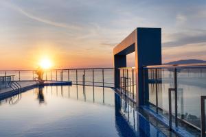 a building on the water with the sunset in the background at DQua Hotel in Nha Trang