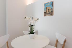 Una mesa blanca con un jarrón de flores. en Villa Poncelet, en París