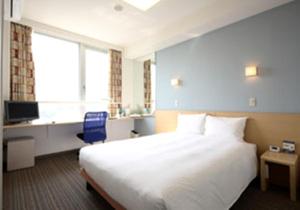 多賀城市にあるスマイルホテル仙台多賀城の白い大型ベッドと青い椅子が備わるホテルルームです。