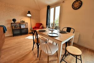 comedor con mesa con sillas y reloj en LE TOIT D'AUVERS - T2- 2e étage, en Auvers-sur-Oise