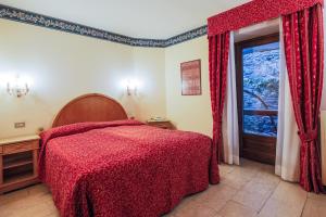 una camera da letto con un letto con una coperta rossa e una finestra di Hotel Courmayeur a Courmayeur