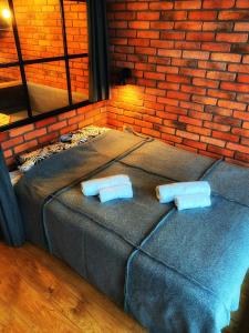 a bed with two pillows in front of a brick wall at the beskid view in Wisła