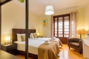 a hotel room with a bed and a chair at Garça Real Flats in Porto