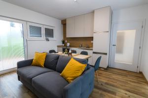 a living room with a blue couch and a kitchen at Apartmány NMNM REZIDENCE NAD MĚSTEM in Nové Město na Moravě