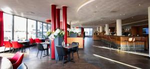 un restaurante con columnas y mesas rojas y un bar en Bastion Hotel Den Haag Rijswijk en Rijswijk