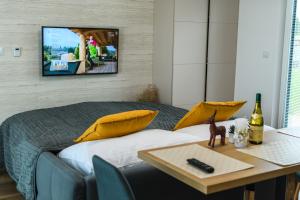 a bedroom with a bed and a table with a tv on the wall at Apartmány NMNM REZIDENCE NAD MĚSTEM in Nové Město na Moravě