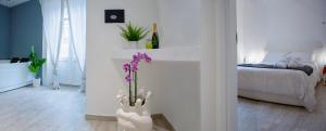 a white room with a bed and a vase with purple flowers at Duomo Luxury Suite Catania in Catania