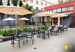 un patio con mesas, sillas y sombrillas en Panamericana Hotel Providencia, en Santiago