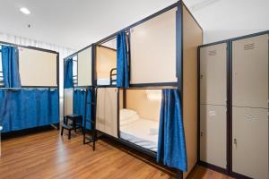 a room with three bunk beds and blue curtains at Amethyst Dorm KLCC in Kuala Lumpur