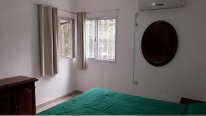 una camera con un letto verde e due finestre di Casa con pileta privada a Tanti Altre 14 foto