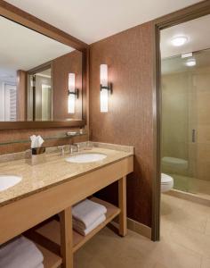 a bathroom with two sinks and a toilet and a mirror at Hyatt Lodge Oak Brook Chicago in Oak Brook