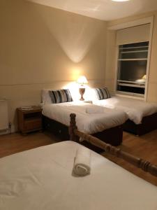 a bedroom with two beds and a lamp on a table at The Georgian House in Glasgow