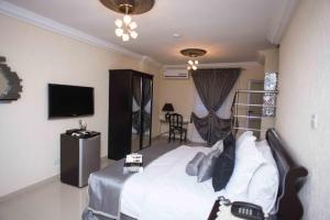 a hotel room with a bed and a television at The Ritzz Exclusive Guest House in Accra
