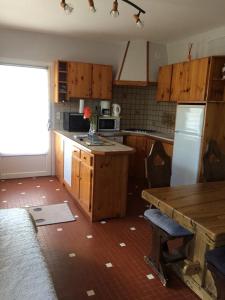 a kitchen with wooden cabinets and a table with a vase of flowers at Appartement été et hiver 1 à 5 pers. Cauterets in Cauterets