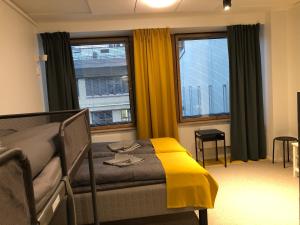 um quarto com uma cama com um cobertor amarelo em Moi Aikatalo Hostel Helsinki em Helsinque