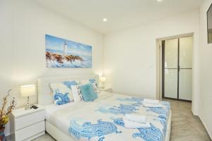 a white bedroom with a bed with blue and white pillows at Apartments Muminovic in Dubrovnik
