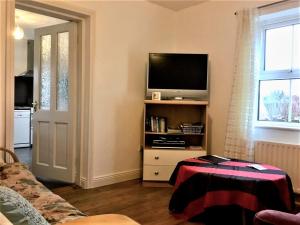 a living room with a television on a shelf at Ravens Oak, West Cork in Bantry