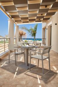 een tafel en stoelen op een balkon met uitzicht op de oceaan bij Sempre Viva Suites in Monemvasia