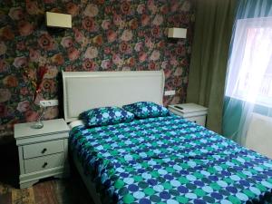 a bedroom with a bed with blue and green sheets at Meny Apartaments in Codlea