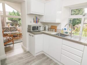 a kitchen with white cabinets and a sink at The Bothy in Sedbergh