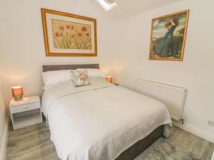 a bedroom with a white bed and a painting on the wall at The Bothy in Sedbergh