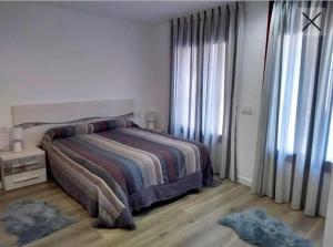 ein weißes Schlafzimmer mit einem Bett und einem Fenster in der Unterkunft Apartamento totalmente reformado en 1ª linea in Palamós