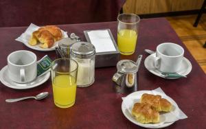 una mesa con platos de bollería y vasos de zumo de naranja en Hotel La Argentina en San Bernardo