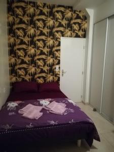 - une chambre avec un lit violet et un mur dans l'établissement Résidence Pearl, à Nice
