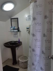 a bathroom with a sink and a shower curtain with writing on it at Hostal Casona de Chorrillos in Viña del Mar