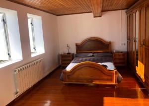 1 dormitorio con 1 cama de madera y 2 ventanas en A Casa do Chico, en Ourense