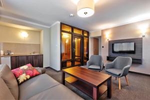 a living room with a couch and chairs and a tv at Hotel Leśny in Białystok