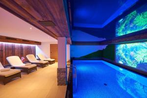 an indoor pool with an aquarium in a room at Boutique Hotel Herzhof - Garni-Appartements - Adults Only in Riezlern