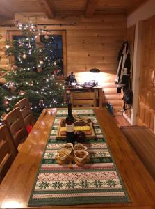a table with a bottle of wine and a christmas tree at Kiwi Chalet in Kupres