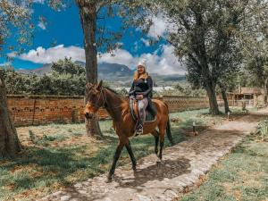 a woman riding a horse in a field at Hosteria Papagayo Cotopaxi in Machachi