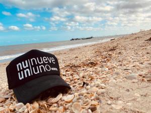 Un cappello nero seduto su una spiaggia rocciosa di Nueve Uno Hostel a Ríohacha