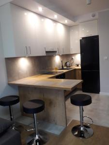 a kitchen with two bar stools and a black refrigerator at Apartament Wiosenna in Białystok