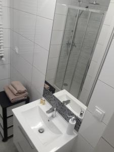 Un baño blanco con lavabo y ducha. en Apartament Wiosenna, en Białystok