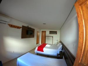 a hotel room with two beds and a tv at Pousada Marotta in Ouro Preto
