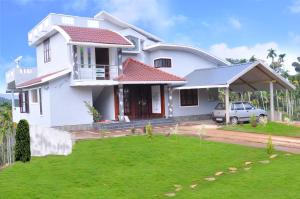 una casa blanca con un coche aparcado delante de ella en Chamayam Holiday Villa, en Meenangadi