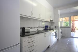 a white kitchen with white cabinets and a sink at Atlantic Palm Garden Residence in Caniço