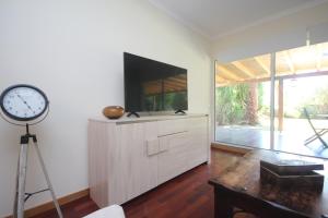 ein Wohnzimmer mit einer Uhr und einem TV an der Wand in der Unterkunft Atlantic Palm Garden Residence in Caniço