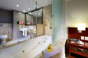 a bathroom with a tub and a toilet and a sink at Grand Palladium Imbassaí Resort & Spa - All Inclusive in Imbassai