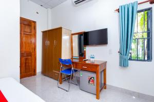 una camera da letto con scrivania, computer e sedia blu di OYO 745 Minh Duc Guest House a Nha Trang