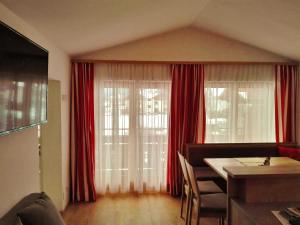 a living room with red curtains and a dining room table at Ferienhaus Bergland in Flachau