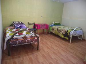 two beds sitting in a room with wooden floors at Hotel Sueños del Chuncho in Yauyos