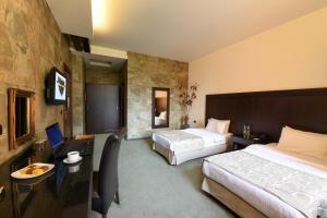 ein Hotelzimmer mit zwei Betten und einem Schreibtisch in der Unterkunft Reston Hotel in Jounieh