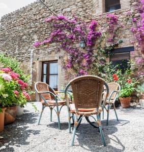 3 sillas y una mesa frente a un edificio con flores en Turismo Rural Calaliu en Peratallada