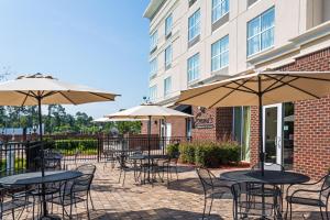 eine Außenterrasse mit Tischen, Stühlen und Sonnenschirmen in der Unterkunft Holiday Inn Statesboro-University Area, an IHG Hotel in Statesboro